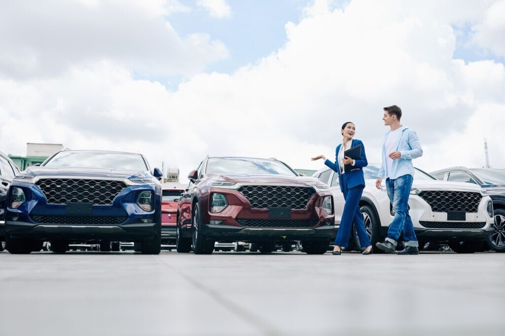 cheerful-saleswoman-showing-cars-to-a-young-man-2026-01-07-07-05-11-utc